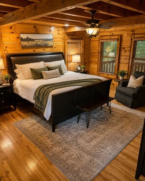 A wooden cabin bedroom with a bed, bedside tables, a bench, and a chair. - "Starlake" A huge waterfront 5 bedroom estate only 15min to downtown Blueridge. (Mineral Bluff)