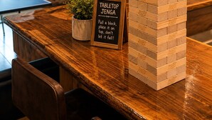 Ein Jenga-Spiel aufgebaut auf einer Holztresen, mit einem Schild, das Spielanleitungen gibt.
