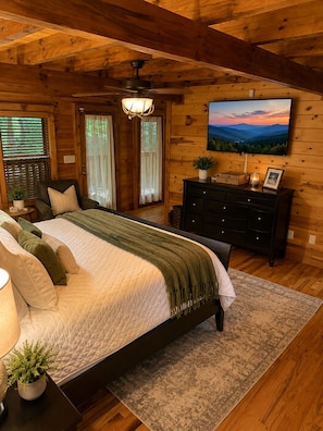 Un dormitorio con cama, cómoda, mesita de noche, lámpara, planta y un cuadro en la pared.