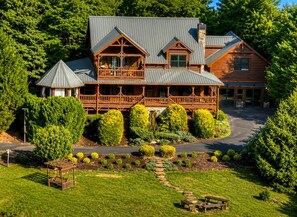 Ein großes, zweistöckiges Chalet mit umlaufender Veranda, einem Steinkamin und einem gepflegten Garten.