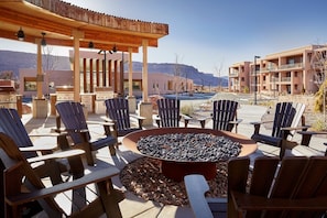 An outdoor seating area with Adirondack chairs and a fire pit, surrounded by a wooden pergola and a view of a mountain. - Moab | Adventure Desert Retreat | Pool + Hot Tub (Moab)