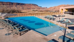 Une piscine avec des chaises longues, un espace aménagé au bord de la piscine et une vue sur les montagnes en arrière-plan.