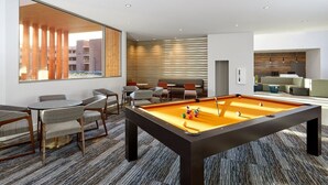 Une pièce moderne dotée d’une table de billard, d’un coin salon et de grandes fenêtres.