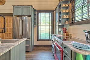 Eine Küche mit einem Edelstahl-Kühlschrank, einem Herd und einem Fenster mit Jalousien.