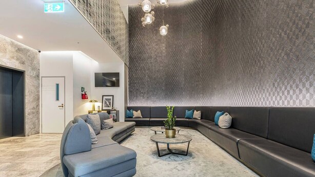 A modern lounge area with a grey sofa, a round coffee table, and a patterned wall. - Mariner Resort Style Escape Where City meets Coast (Port Melbourne)