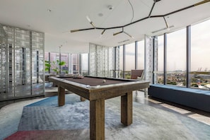 Ein moderner Pooltisch in Innenräumen mit Blick auf die Stadt, einem Sitzbereich und einer dekorativen Decke.