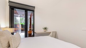 A bedroom with a bed, a nightstand, a lamp, and a view through a sliding door to an outdoor area. - Mariner Resort Style Escape Where City meets Coast (Port Melbourne)