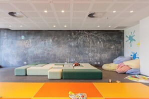 A modern lounge area with a large chalkboard wall, colorful seating, and a playful floor design. - The Parkhouse Riverside Living with Pool and Sauna (Abbotsford)