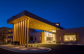 A modern hotel with a prominent overhang, large windows, and a well-lit entrance. - Moab | Adventure Retreat | Pool + Hot Tub | 2BR (Moab)