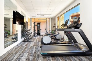 A hotel gym with treadmills, dumbbells, and exercise equipment.