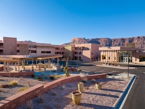 A modern hotel with a covered outdoor area, a parking lot, and a mountainous backdrop. - Moab | Adventure Retreat | Pool + Hot Tub | 2BR (Moab)