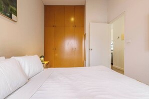 A bedroom with a bed, a wardrobe, and a nightstand with a lamp. - Tullo Place Richmond Heritage with Artistic Charm (Richmond)