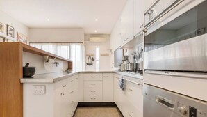 A modern kitchen with white cabinetry, a Bosch refrigerator, and a countertop with various kitchen items. - Tullo Place Richmond Heritage with Artistic Charm (Richmond)