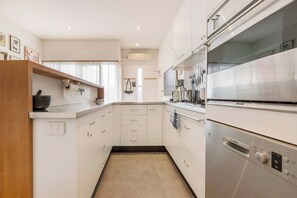 A modern kitchen with white cabinetry, a Bosch refrigerator, and a countertop with various kitchen items. - Tullo Place Richmond Heritage with Artistic Charm (Richmond)