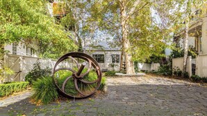 A paved courtyard with a large metal sculpture, surrounded by trees and fences. - Tullo Place Richmond Heritage with Artistic Charm (Richmond)