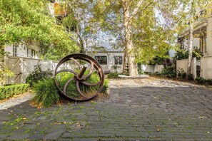A paved courtyard with a large metal sculpture, surrounded by trees and fences. - Tullo Place Richmond Heritage with Artistic Charm (Richmond)
