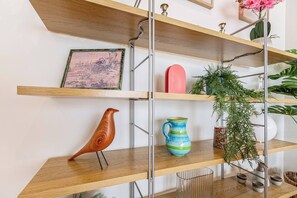 A wooden shelf with a framed picture, a bird sculpture, a blue and green pitcher, and a potted plant. - Tullo Place Richmond Heritage with Artistic Charm (Richmond)