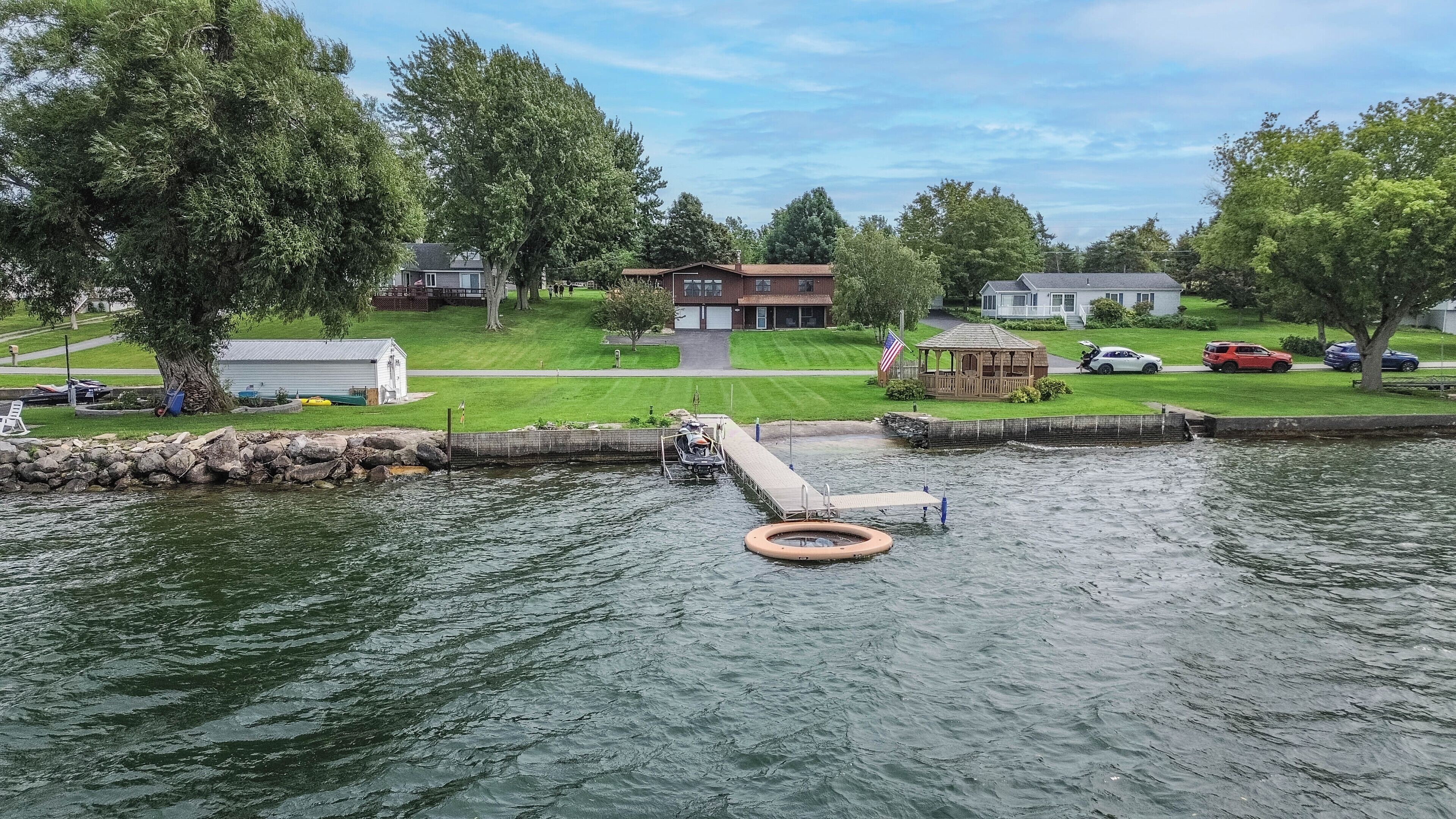 A residential area with a dock, a small boat, and a gazebo.