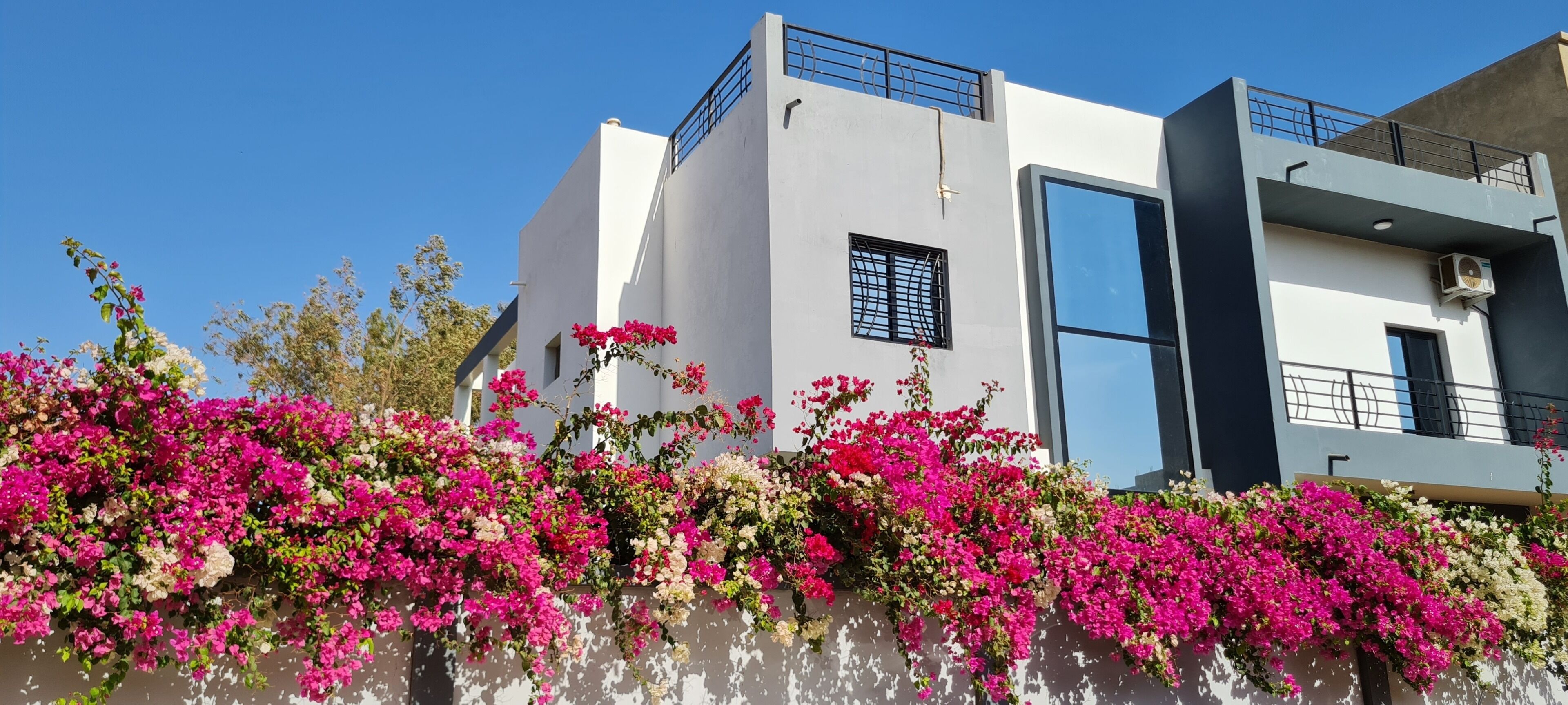 A modern building with a white facade, a balcony, and a window.
