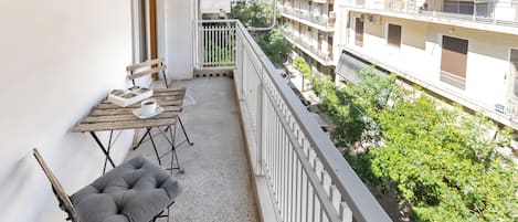 A balcony with a table and chairs, a view of adjacent buildings, and a railing.