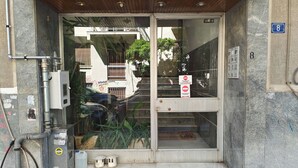 A building entrance with a glass door, a metal utility box, and a number sign. - Athenian Apt with Balcony Pagkrati by GHH (Athina)