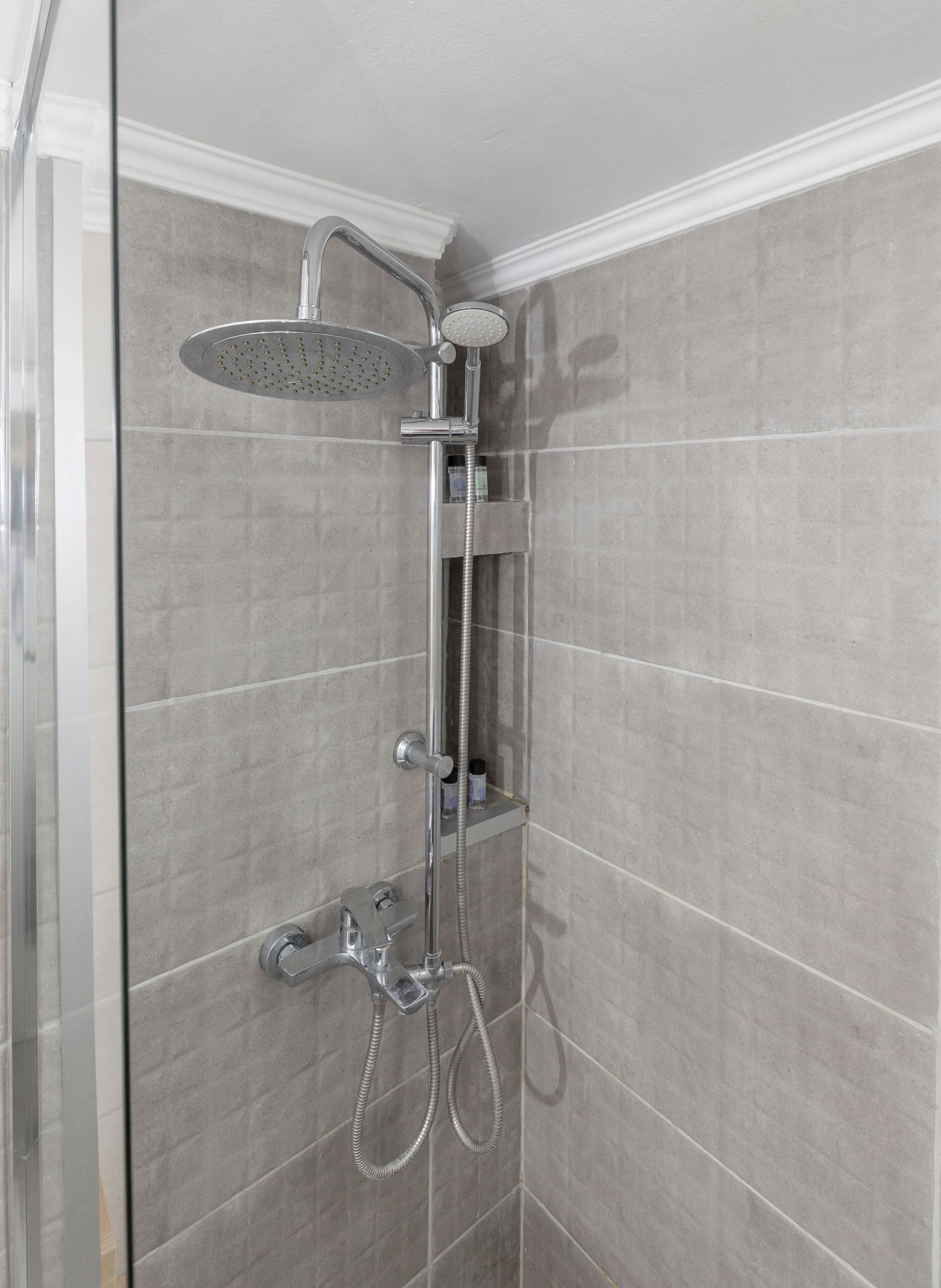 Eine Dusche mit Duschbrause, Wandarmatur und Handbrause.