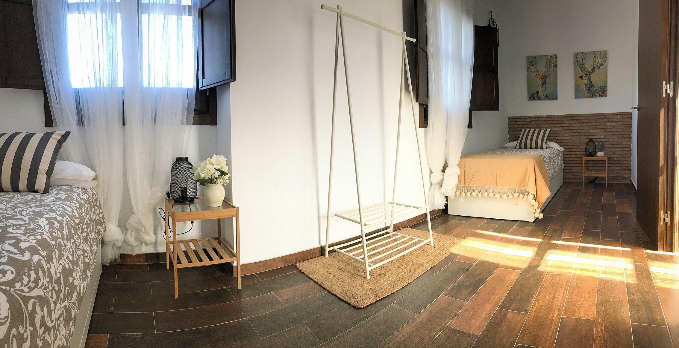 Une chambre à coucher avec un lit, un fauteuil suspendu, une petite table avec un vase et un téléviseur fixé au mur.
