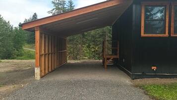 Un espace extérieur abrité, avec un chemin de gravier menant à un bâtiment doté d’un toit en métal.