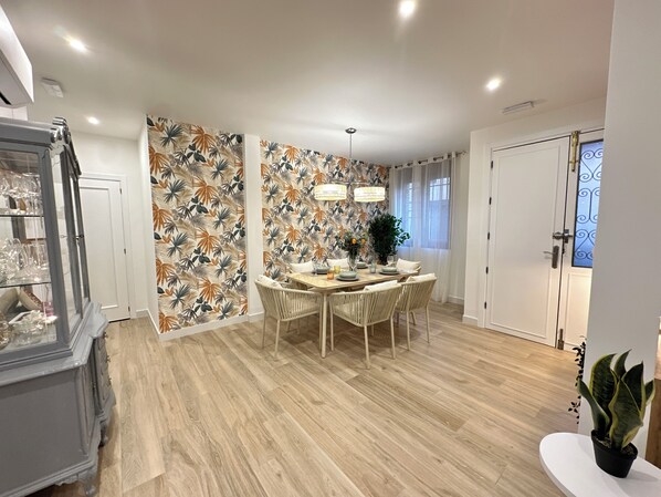 A dining area with a round table, chairs, and a decorative wall with a leaf pattern.