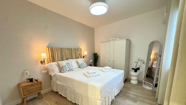 A bedroom with a bed, bedside tables, a wardrobe, a mirror, and a ceiling light.