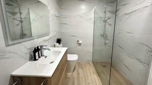 A modern bathroom with a glass shower enclosure, a wooden vanity with a sink, and a toilet.