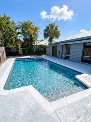 A rectangular swimming pool with clear blue water, surrounded by a stone deck. - Rocky Point Retreat - Private Pool - Boat Parking - 3BR (Stuart)