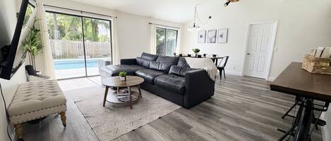 A spacious living room with a sectional sofa, a coffee table, and a dining area with a table and chairs.