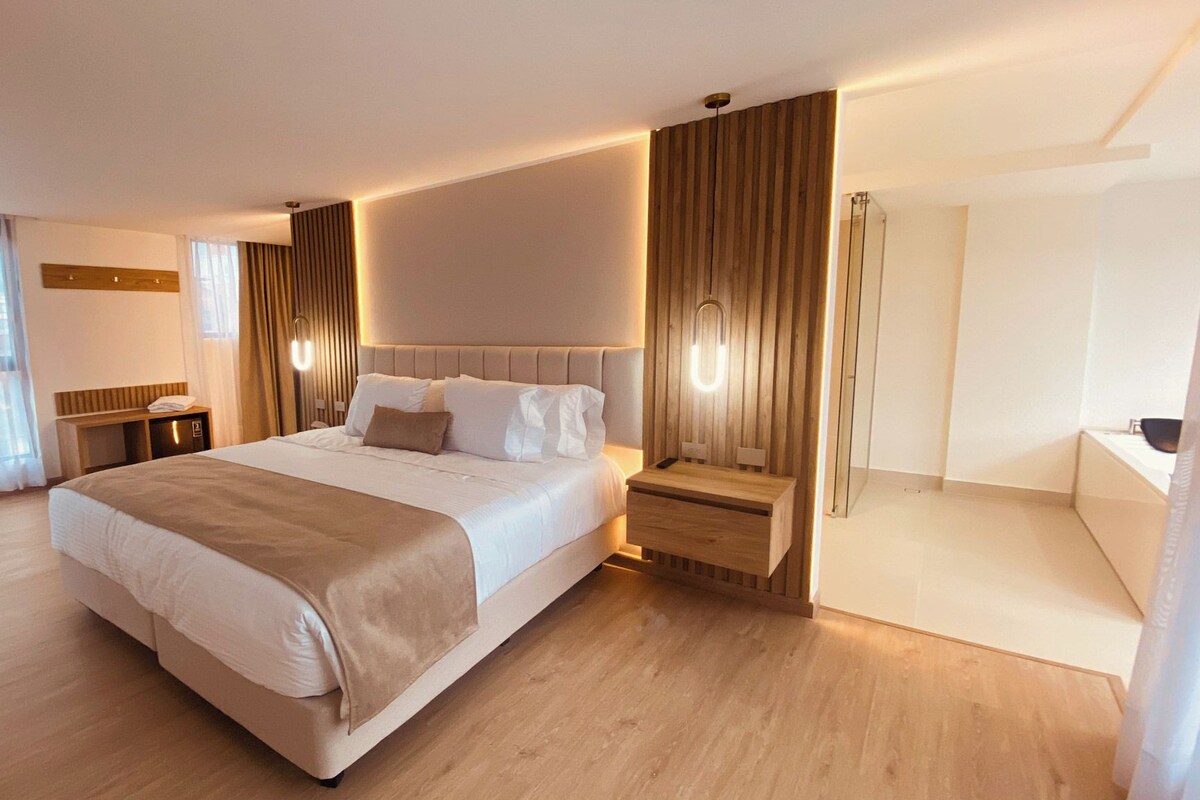 A hotel room with a large bed, bedside tables, a mirror, and a view of the city.