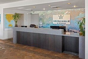 Un comptoir d’accueil avec une enseigne indiquant « WORLDMARK BY WYNDHAM », une carte accrochée au mur et une plante en pot.
