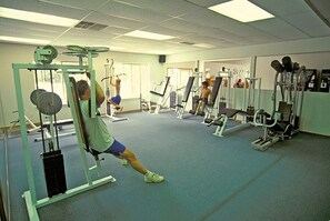 Une salle de sport équipée de divers appareils d’entraînement, notamment des machines à poids et des poids libres.