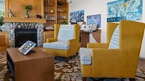 A living room with a fireplace, two yellow armchairs, a coffee table, and a bookshelf.