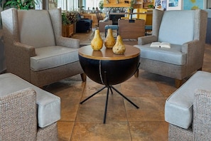 A modern living room with two grey sofas, a round black coffee table, and a bookshelf in the background.