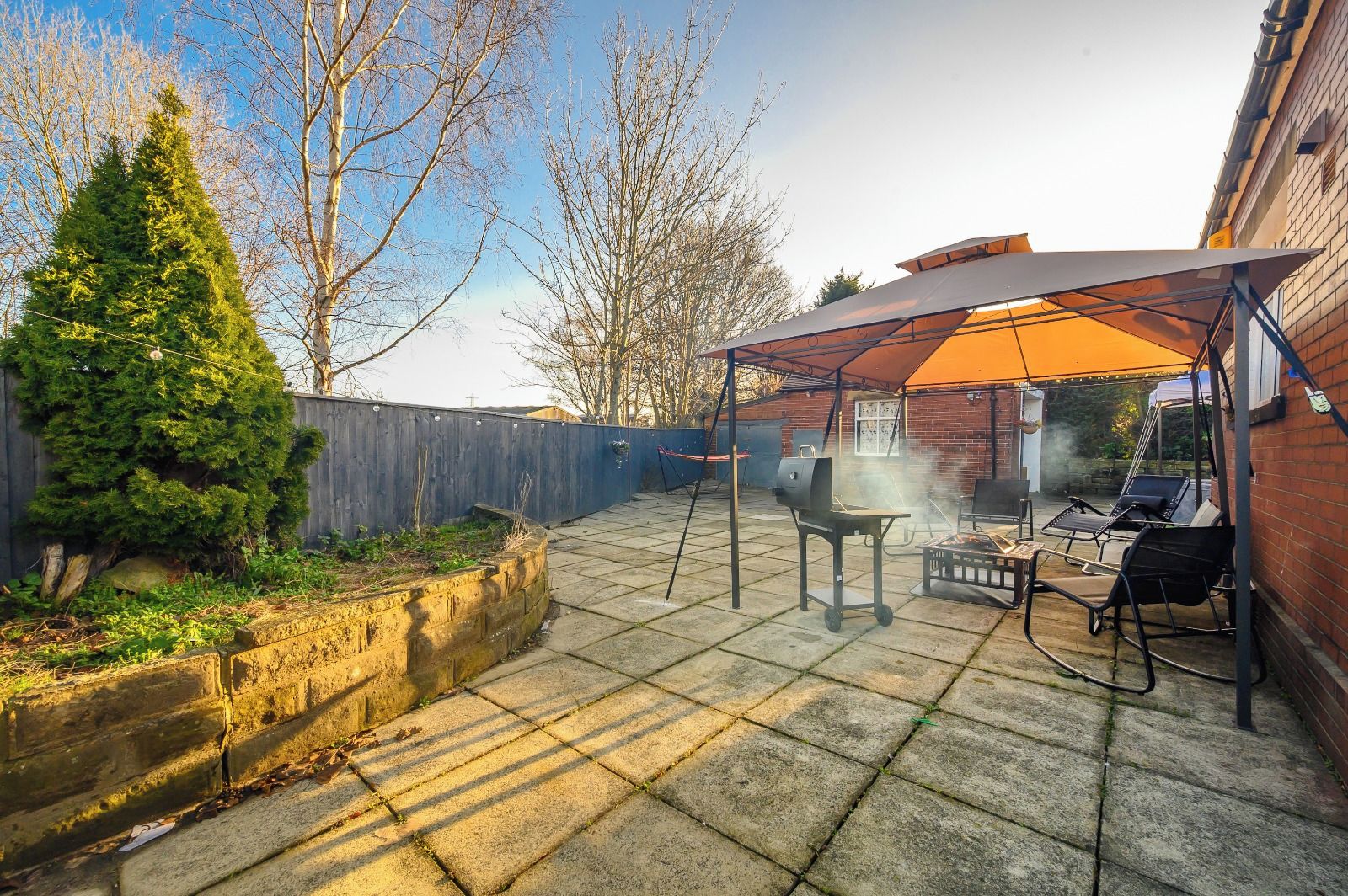 A backyard patio with a grill, outdoor furniture, and a covered seating area.