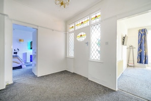 A room with a carpeted floor, a door with a window, and a hallway leading to another room. - Amazing House with Hot Tub & Game Room (West Yorkshire)