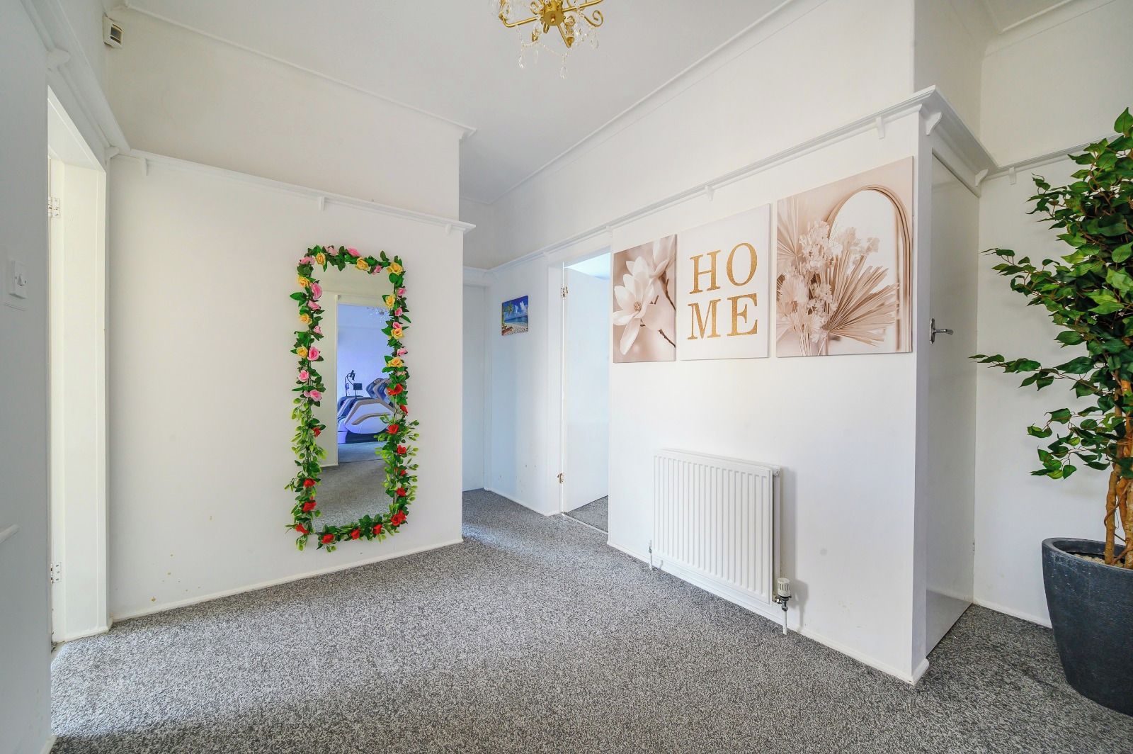 A hallway with a mirror, a radiator, and a plant.