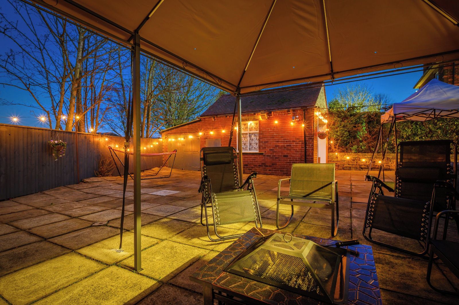 An outdoor patio with a covered area, seating, and a barbecue grill.