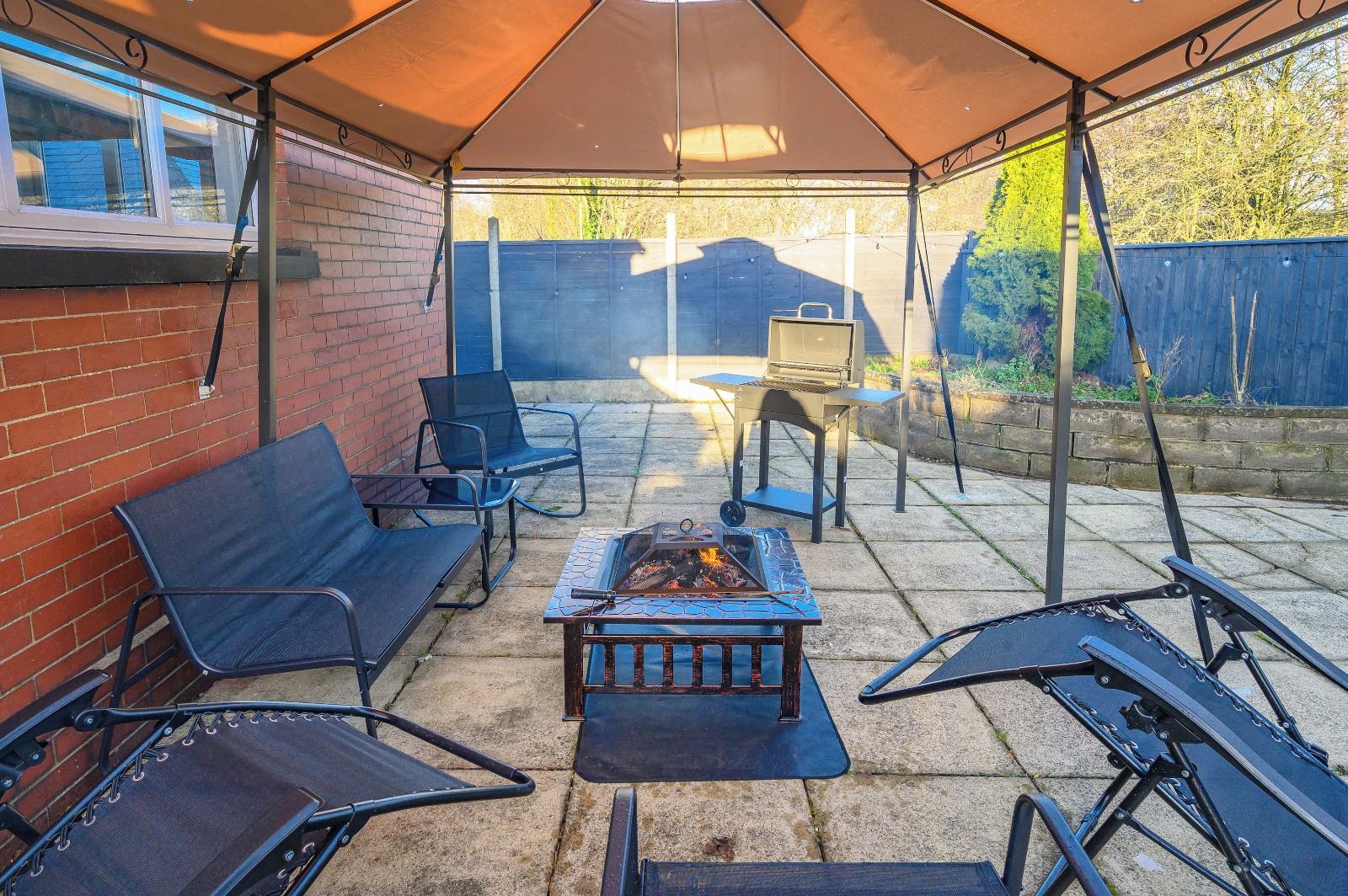 An outdoor patio with a barbecue grill, seating area, and a covered section.