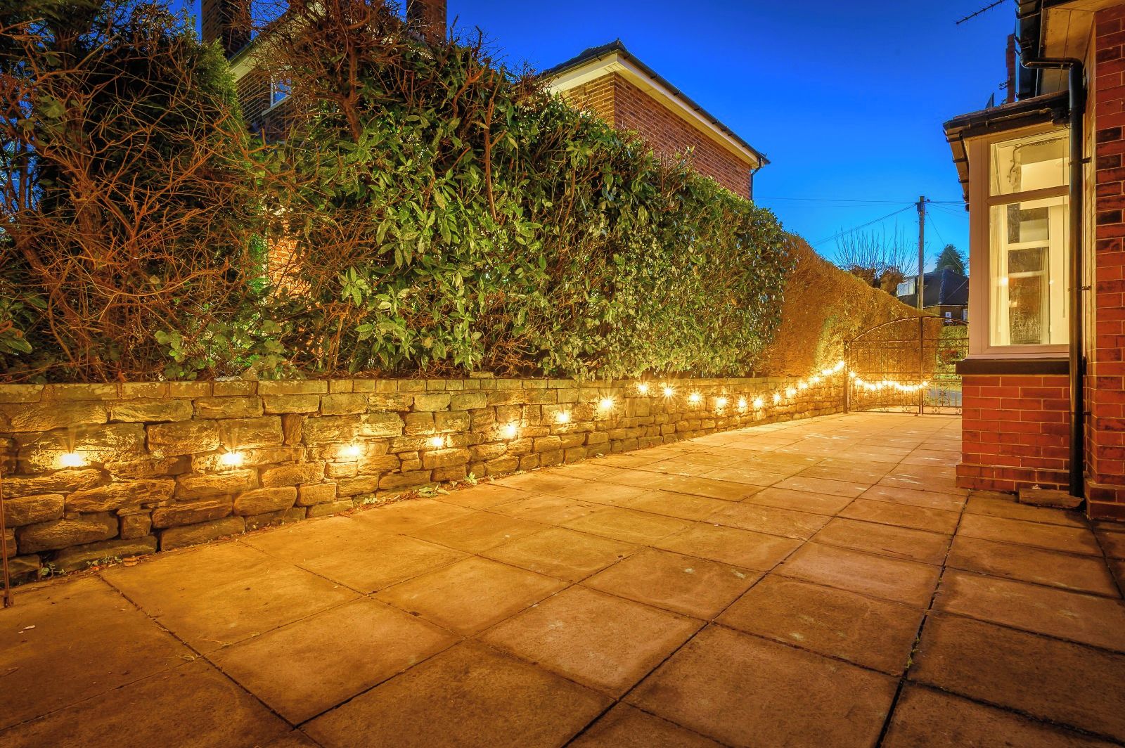 A paved pathway with a stone wall on one side and a brick building on the other.