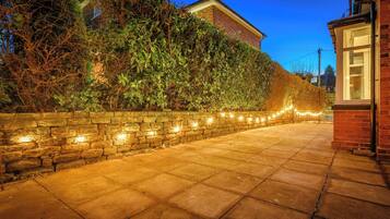 A paved pathway with a stone wall on one side and a brick building on the other.