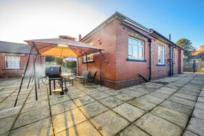 A brick house with a patio area featuring a barbecue grill and outdoor seating. - Amazing House with Hot Tub & Game Room (West Yorkshire)