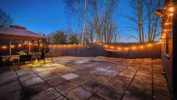 A patio area with a covered seating area, a hammock, and string lights.