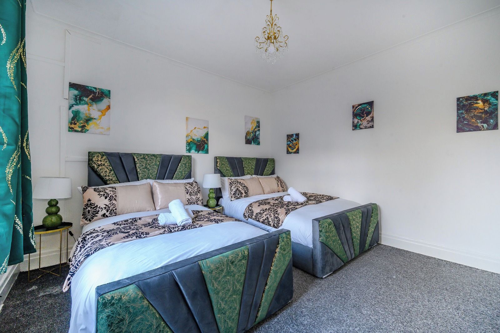 A double bed with a patterned bedspread, a bedside table with a lamp, and artwork on the walls.