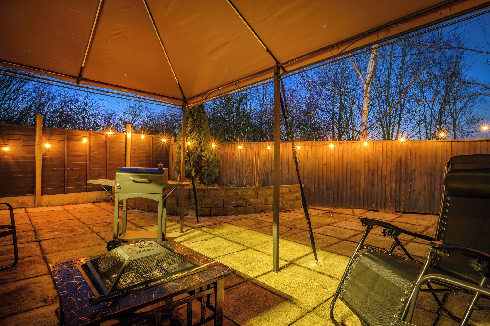 Une terrasse extérieure dotée d’un espace couvert, d’un barbecue, d’une table et de chaises.