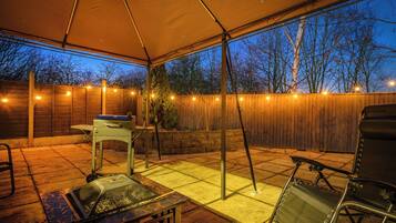 Une terrasse extérieure dotée d’un espace couvert, d’un barbecue, d’une table et de chaises.